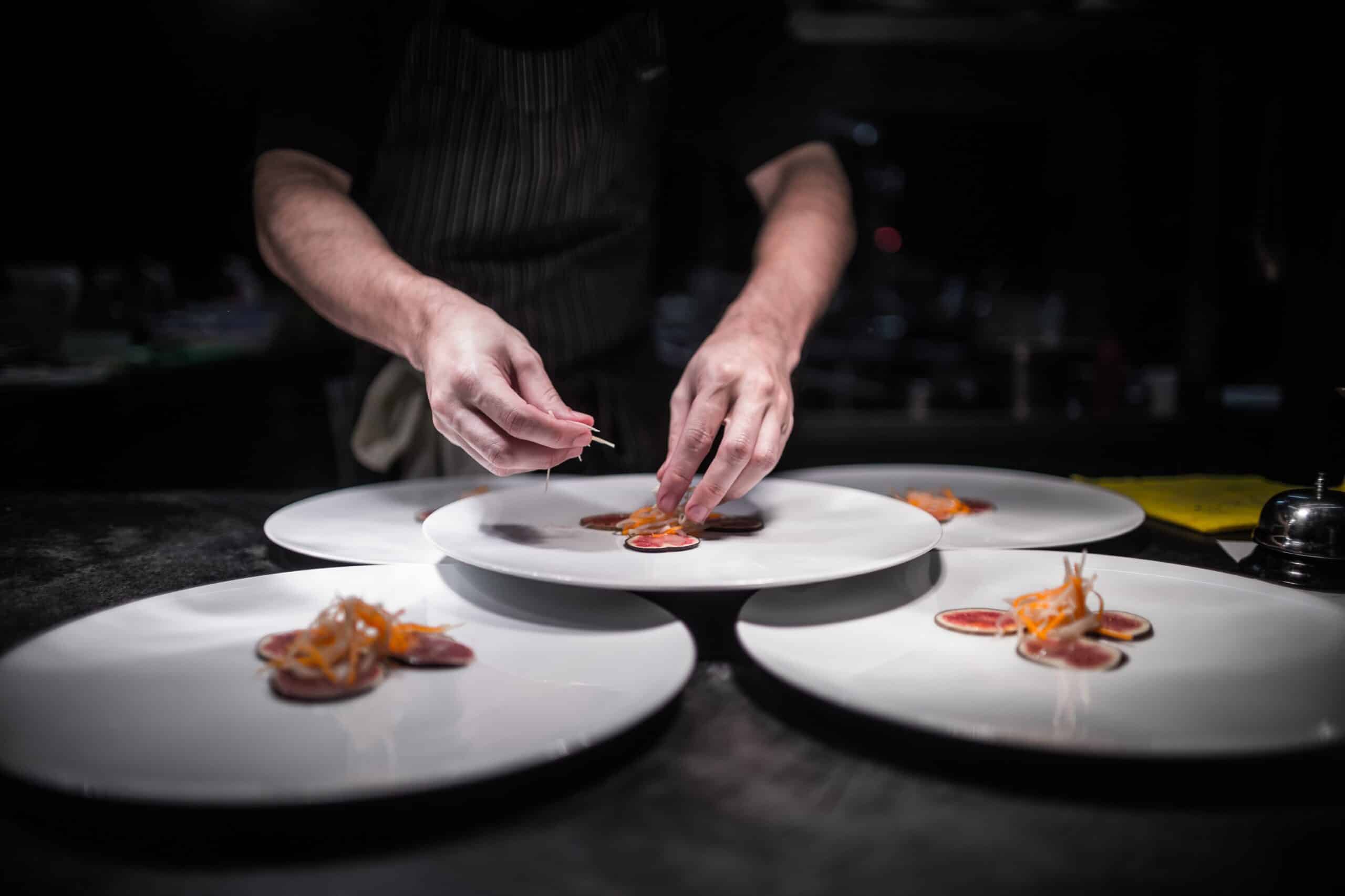 Chef gourmet en cuisine sombre, quatre plats.