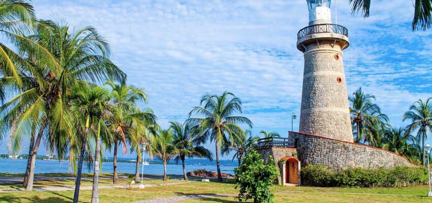Côte paradisiaque avec phare ensoleillé et palmiers.