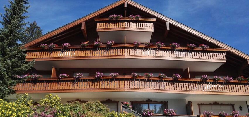 Chalet alpin avec balcons fleuris, ciel bleu clair.