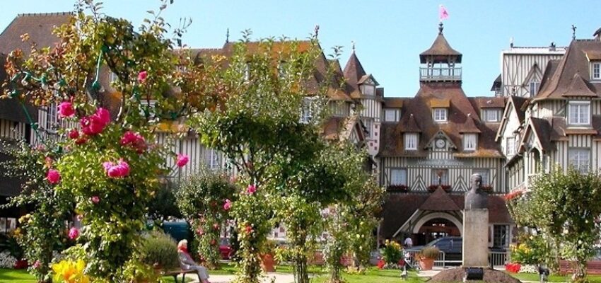 Place de Deauville avec des fleurs, de la verdure et des gens.