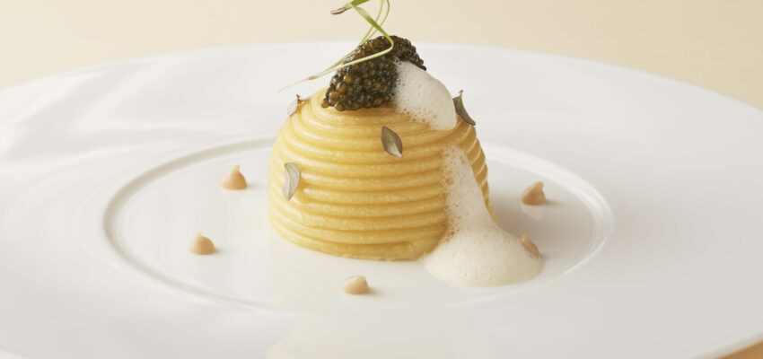 Pâtes élancées au caviar sur assiette blanche.