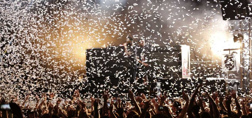 Concert animé, foule joyeuse et confettis tombant.