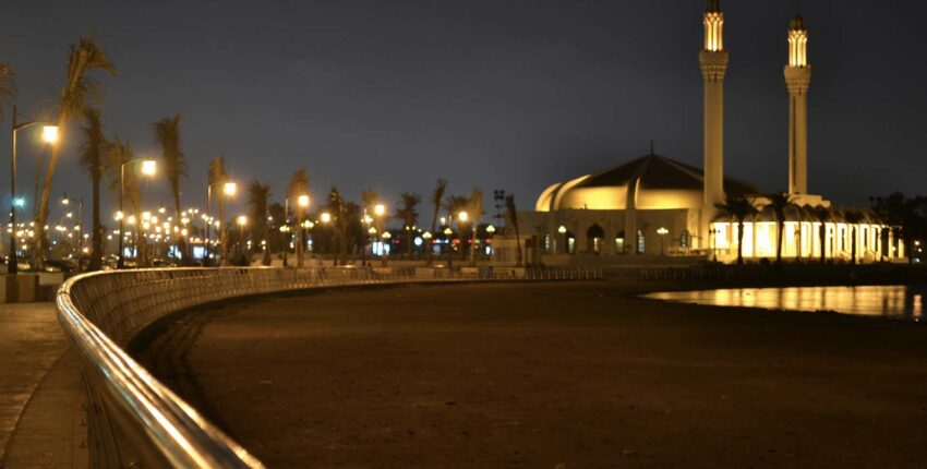Promenade nocturne avec mosquée illuminée et minarets.