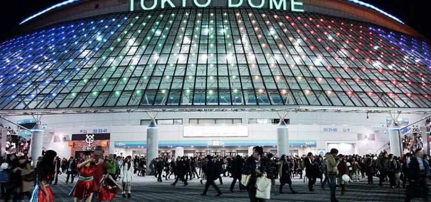 Dôme nocturne illuminé au Tokyo Dome, foule présente.