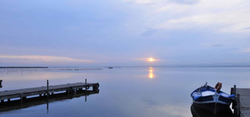 Un lac serein au coucher du soleil avec quai et bateau.