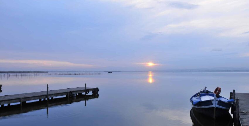 Un lac serein au coucher du soleil avec quai et bateau.