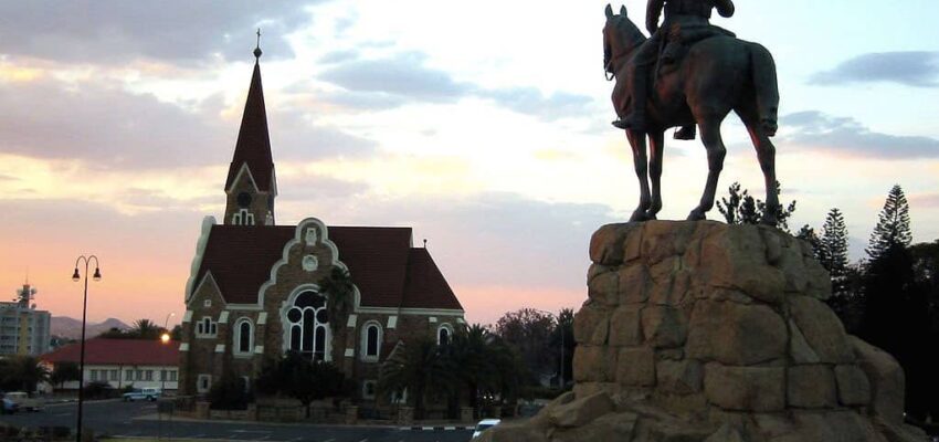 Coucher de soleil sur statue équestre et église.
