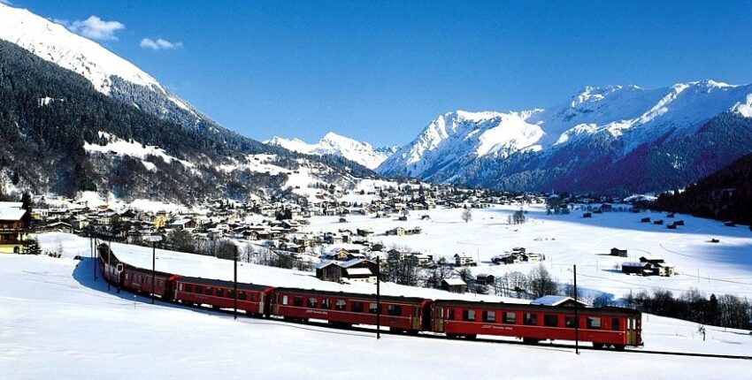 Train rouge, montagnes enneigées, ciel bleu, Klosters.