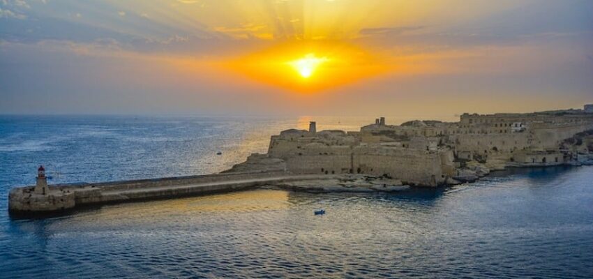 Coucher de soleil sur forteresse côtière et phare.
