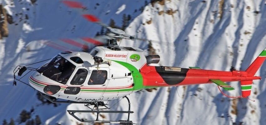 Location hélicoptère - Hélicoptère multicolore survolant montagnes enneigées.
