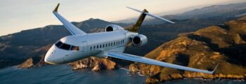 Le jet privé Bombardier Global 6000 en vol avec un couché de soleil, la mer et des montages