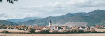 Grande bâtisse avec dôme, voitures vintage, ciel bleu.