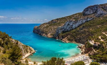 Plage isolée en Espagne entourée de falaises et de verdure.